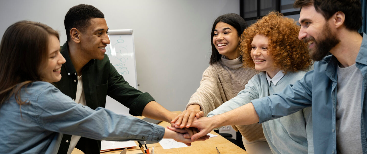 Equipe de vendas com as mãos sobrepostas gerando engajamento entre equipe